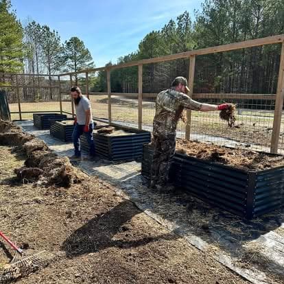 Family filling raised beds with compost