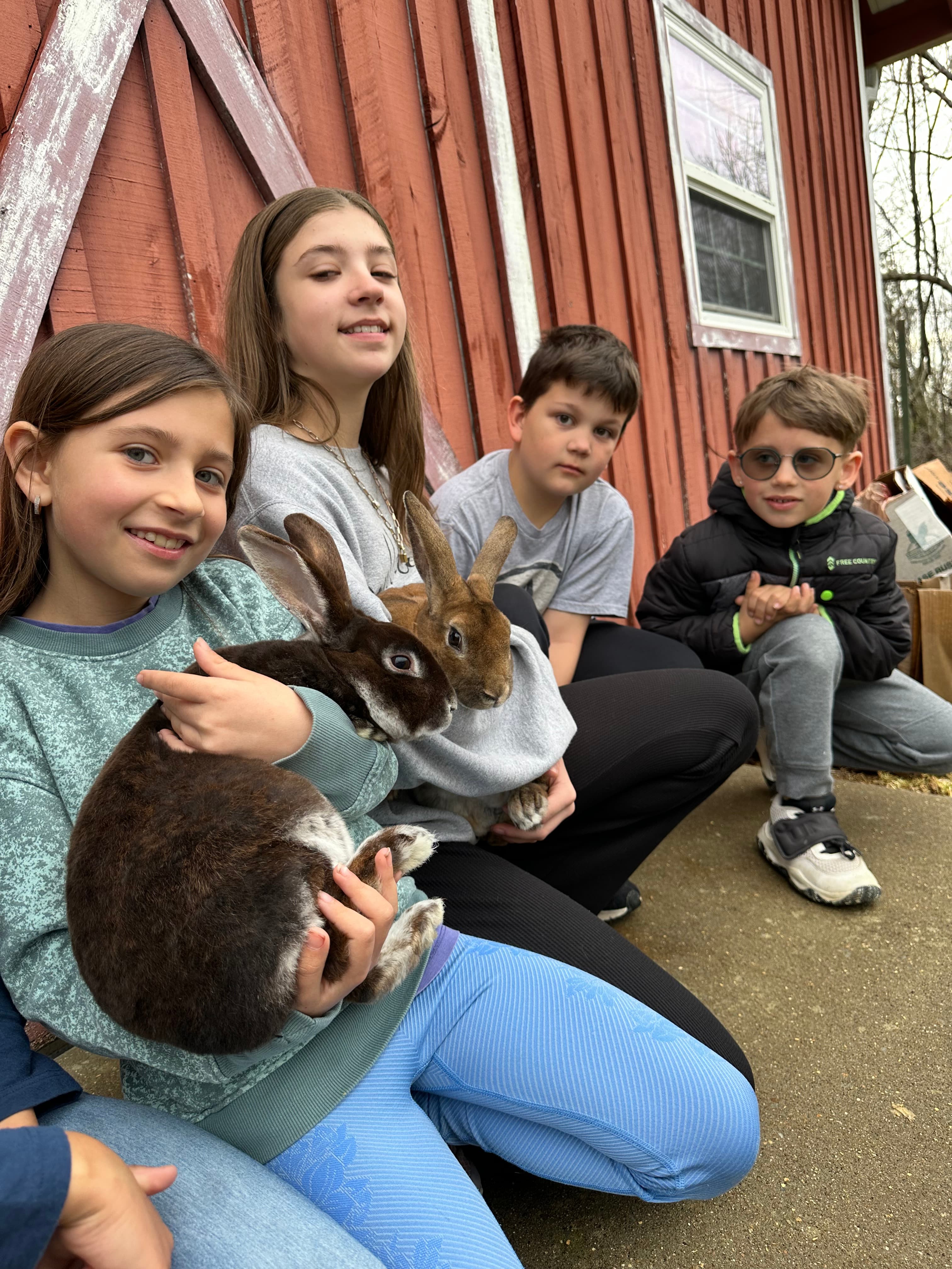 Family sitting outside the barn with a rabbit in their laps